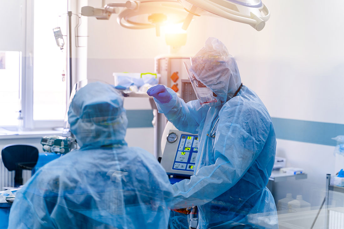 Two medical professions in intensive care emergency room with artificial lung ventilation monitor in the intensive care unit.